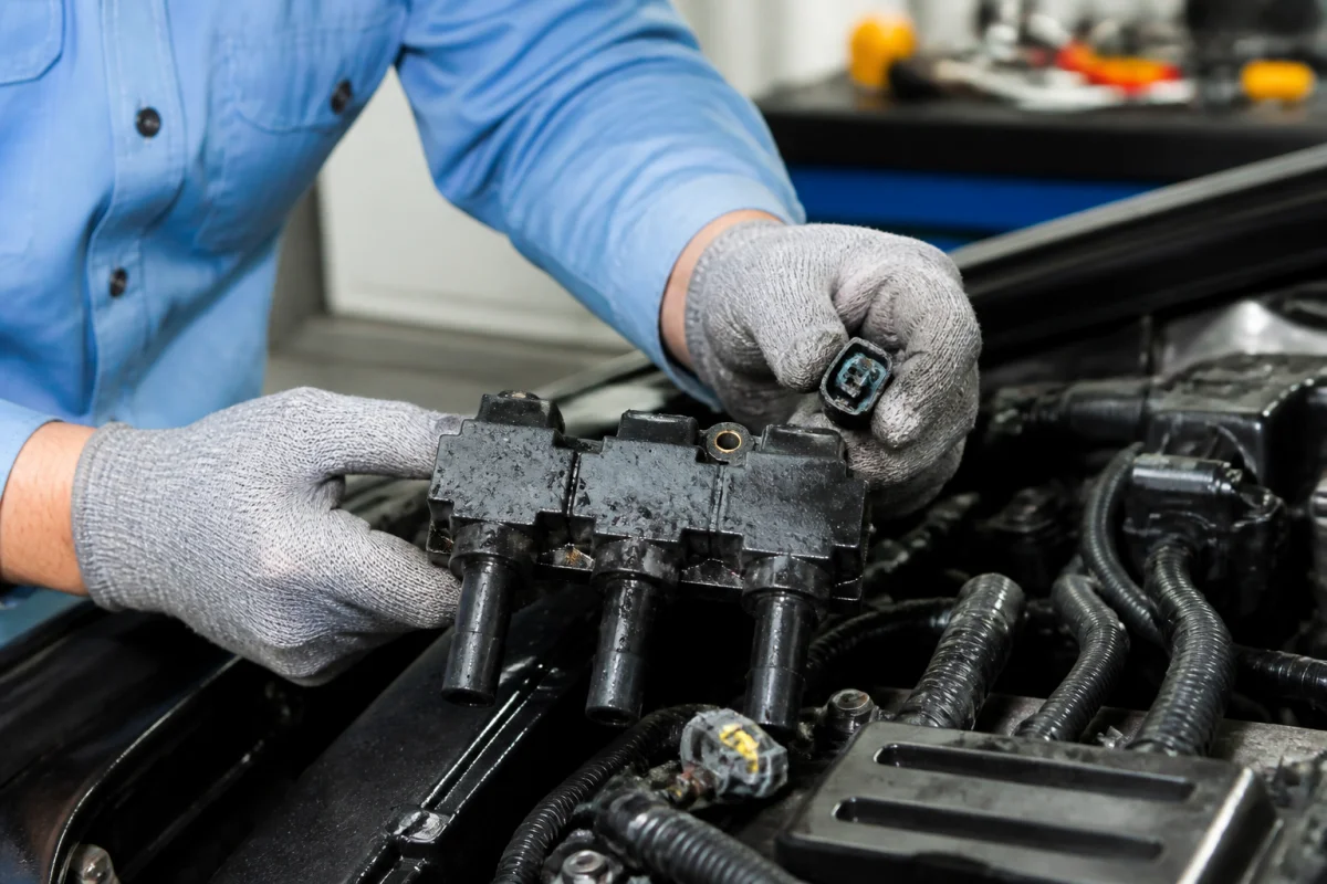 Mécanicien inspectant une bobine d’allumage automobile et ses connecteurs pour détecter fissures, corrosion ou humidité